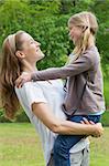 Side view of a smiling mother carrying daughter at the park