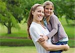 Portrait of a smiling mother carrying daughter at the park