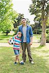 Portrait of a smiling father and son with ball at the park