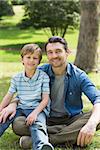 Portrait of a father and young boy sitting at the park