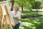 Mature woman painting on canvas in the park