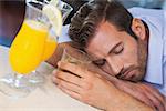 Drunk businessman sleeping on bar beside cocktail at the local bar