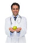 Smiling doctor showing apple to camera on white background