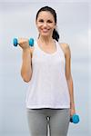 Beautiful young woman doing outdoor morning exercises with weights