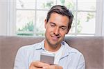 Casual young man reading text message on sofa at home
