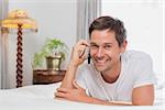 Portrait of a casual young man using mobile phone in bed at home