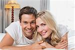 Portrait of a relaxed happy casual young couple resting in bed at home