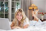 Portrait of a casual young woman using laptop in bed at home