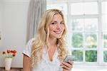 Portrait of a happy young woman reading text message in bed at home