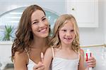 Close-up of a mother and daughter with toothbrush and toothpaste in the bathroom