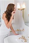 Side view of a young woman brushing teeth in the bathroom