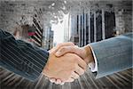 Composite image of business handshake against cityscape on brick wall