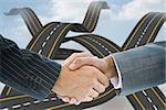 Composite image of business handshake against crossing roads in the sky