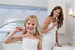 Portrait of a little girl with mother brushing teeth in the bathroom