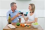 Loving couple toasting wine glasses in the kitchen at home