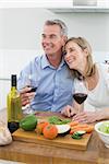 Loving couple with wine glasses in the kitchen at home