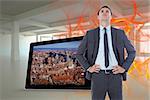 Serious businessman with hands on hips against abstract design in orange