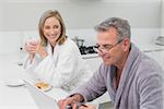 Happy couple in bathrobe doing online shopping through laptop and credit card at home