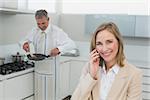 Businesswoman on call while man preparing food in the kitchen at home