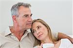 Relaxed loving couple with coffee cup in living room at home