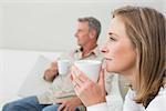 Relaxed couple with coffee cups in living room at home