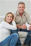 Portrait of a relaxed couple with coffee cup in living room at home
