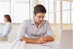 Concentrated young businessman working on blueprints in the office