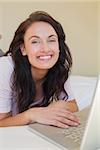 Relaxed woman using laptop while lying in bed at home