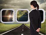 Businesswoman standing against highway under cloudy sky