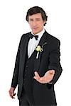 Portrait of confident groom in tuxedo offering hand isolated over white background
