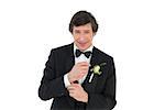 Portrait of smiling groom in tuxedo getting ready over white background