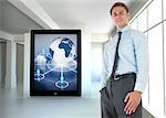 Happy businessman standing with hand in pocket against white room with screen