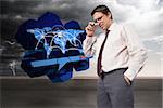 Thinking businessman touching his glasses against balcony and stormy sky