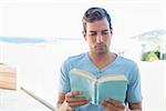 Concentrated young man reading book at home