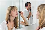 Close-up of a beautiful young woman applying mascara in the bathroom at home