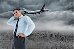 Thinking businessman with hand on head against gloomy city