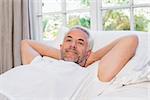 Portrait of a relaxed mature man lying in bed at home