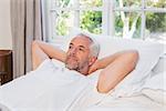 Thoughtful and relaxed mature man lying in bed at home