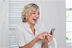 Cheerful mature woman text messaging at home