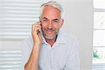 Portrait of a happy mature man using mobile phone at home