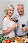 Loving mature couple with wine glasses in the kitchen at home