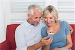 Smiling mature couple reading text message at home