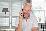 Relaxed mature man using mobile phone at home