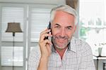 Portrait of a relaxed mature man using mobile phone at home