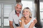 Portrait of a happy mature couple reading text message at home