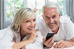 Close-up portrait of a cheerful mature couple reading text message at home