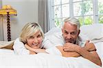 Portrait of a happy mature couple lying in bed at home