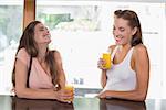 Happy young female friends drinking orange juice at the café