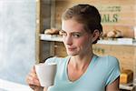 Thoughtful young woman drinking coffee in the coffee shop