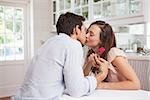 Side view of a loving young couple kissing in the kitchen at home